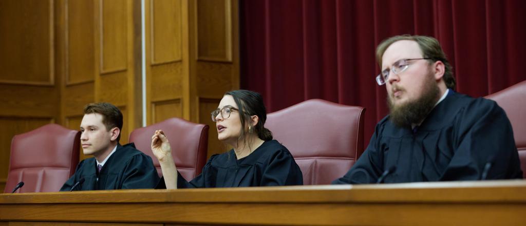 Three students portraying moot court judges in Bell Courtroom.